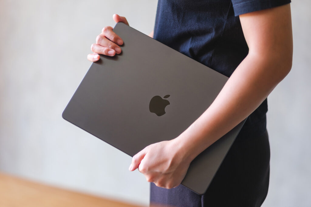 Appleのロゴ、MacBookを持つ手